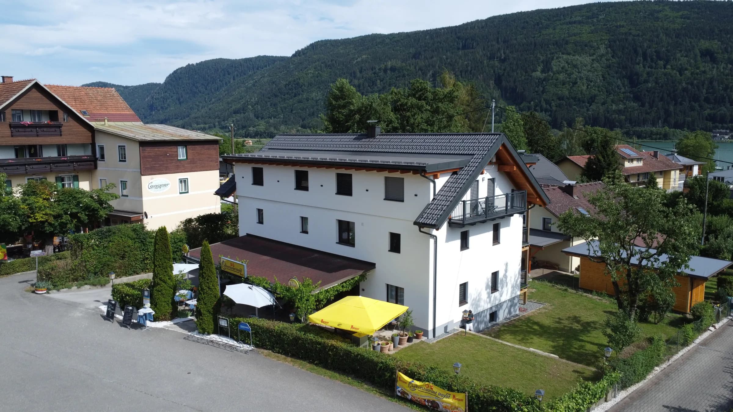 Luftaufnahme des Seerestaurant Hayat mit Zufahrt, Ossiacher See und Bergen