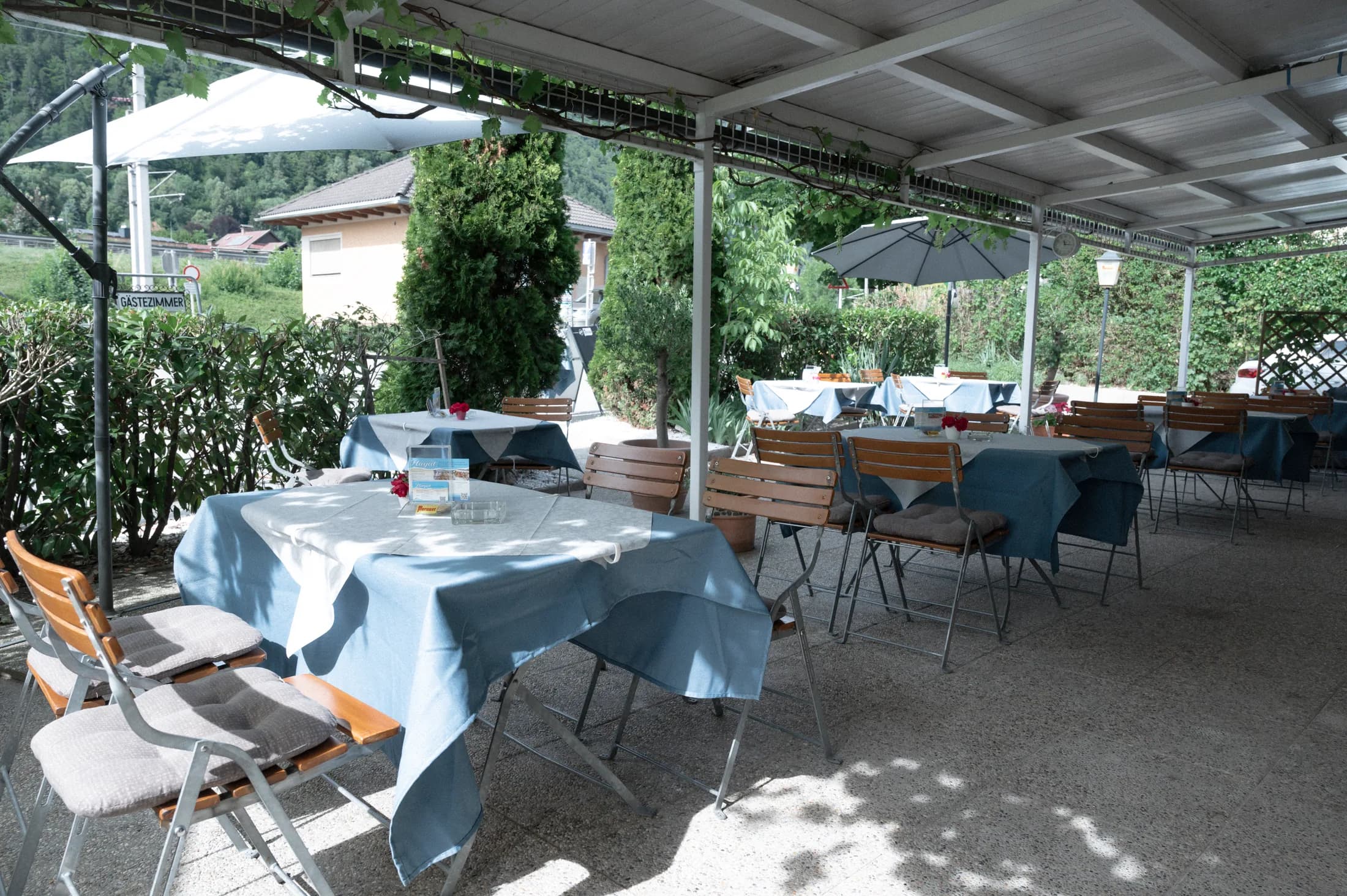 Überdachter Gastgarten mit gedeckten Tischen